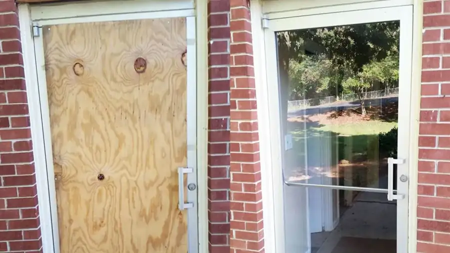 Boarded-up commercial storefront door next to the same door with new glass